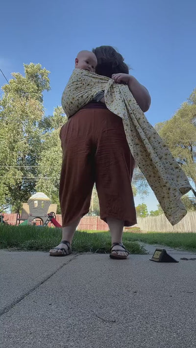 Plus size mother wearing sunflower print plus size baby carrier while dancing