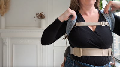 Video demonstrating how to adjust the chest clip on the Lark baby carrier: the wearer points to the buckle, then slides it upward along the shoulder strap to reposition it for a better fit.