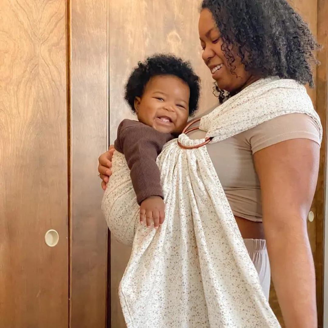 Black mother wearing smiling baby in ring sling baby carrier with terrazzo print.