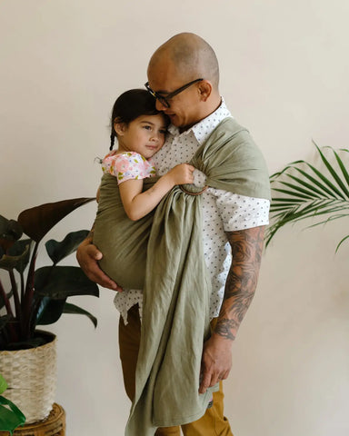 Father wearing toddler in a ring sling