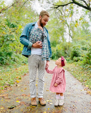 Father wearing newborn in a floral ring sling