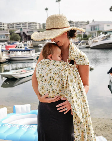 Mother wearing baby in a sunflower pattern ring sling