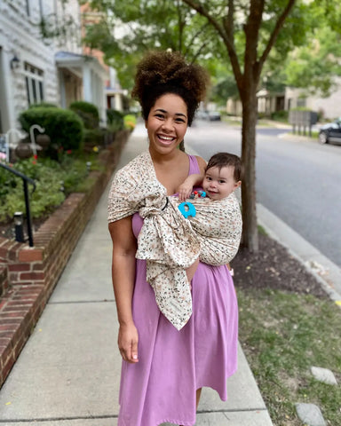 Mother wearing a baby in a floral ring sling