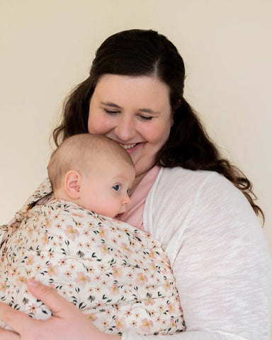 Mother wearing baby in a floral ring sling