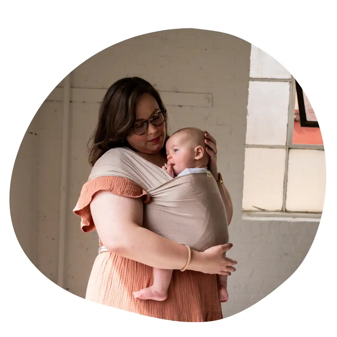 Woman holding baby in a wrap carrier.