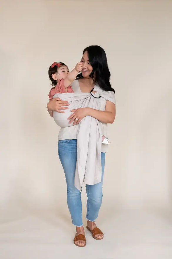 Mother carrying newborn in a taupe moon pattern woven ring sling.